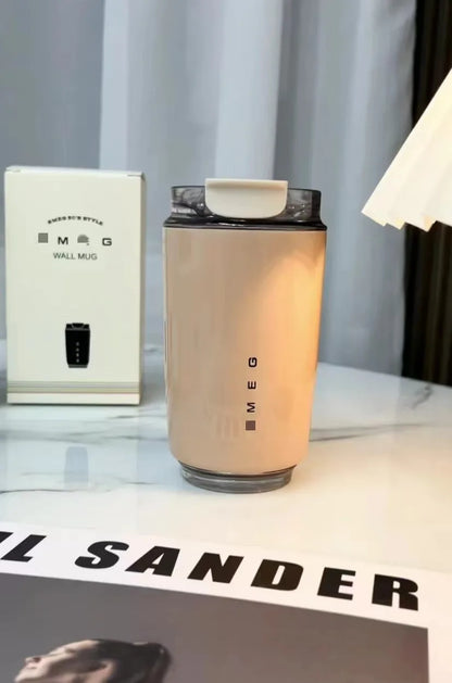 SMEG Beige mug with black lid on a surface, next to a white box labelled 'SMEG'.