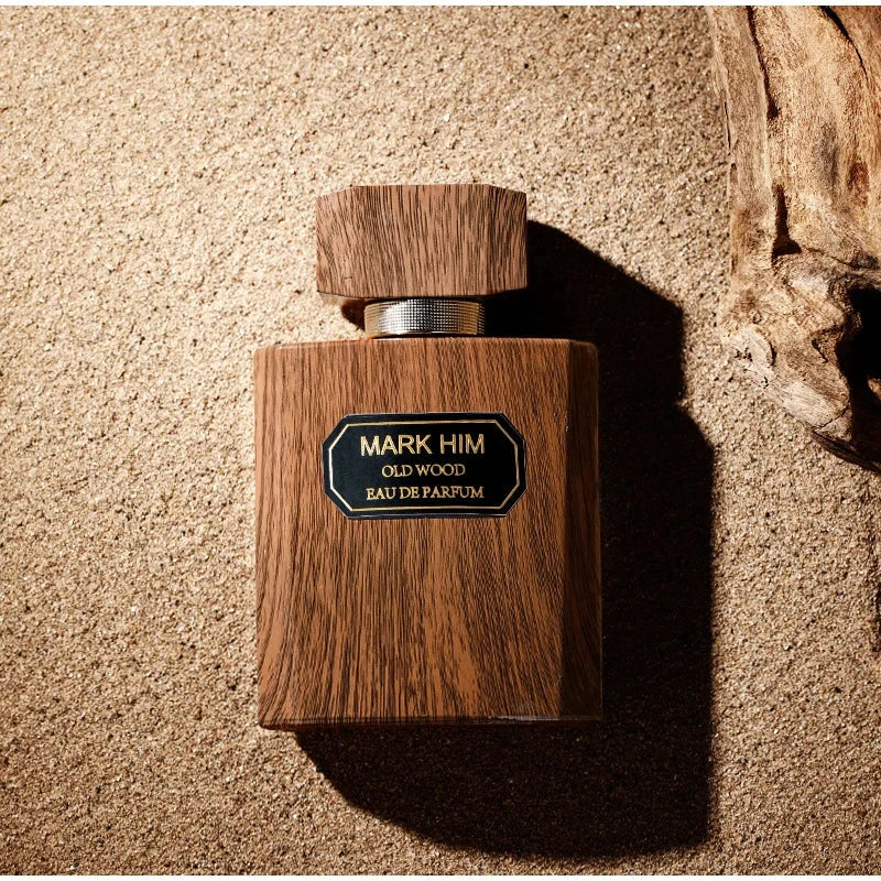Wooden perfume bottle labeled 'Mark Him Old Wood' on a textured surface