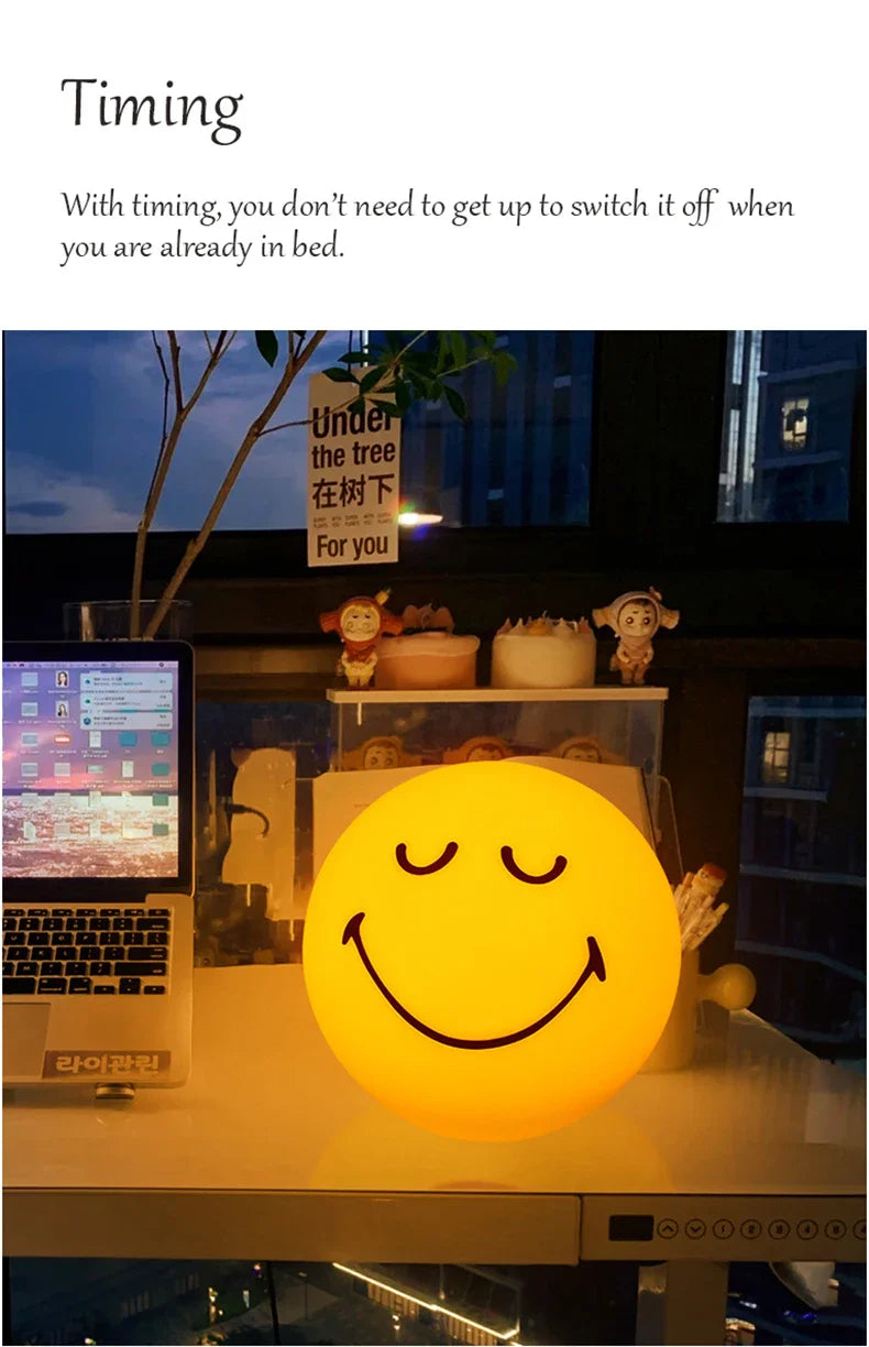 Smiley face night light on a desk with computer and decor in the background