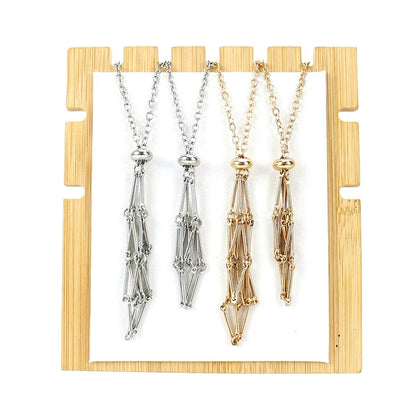 Three necklaces in silver, gold, and rose gold on a wooden stand.