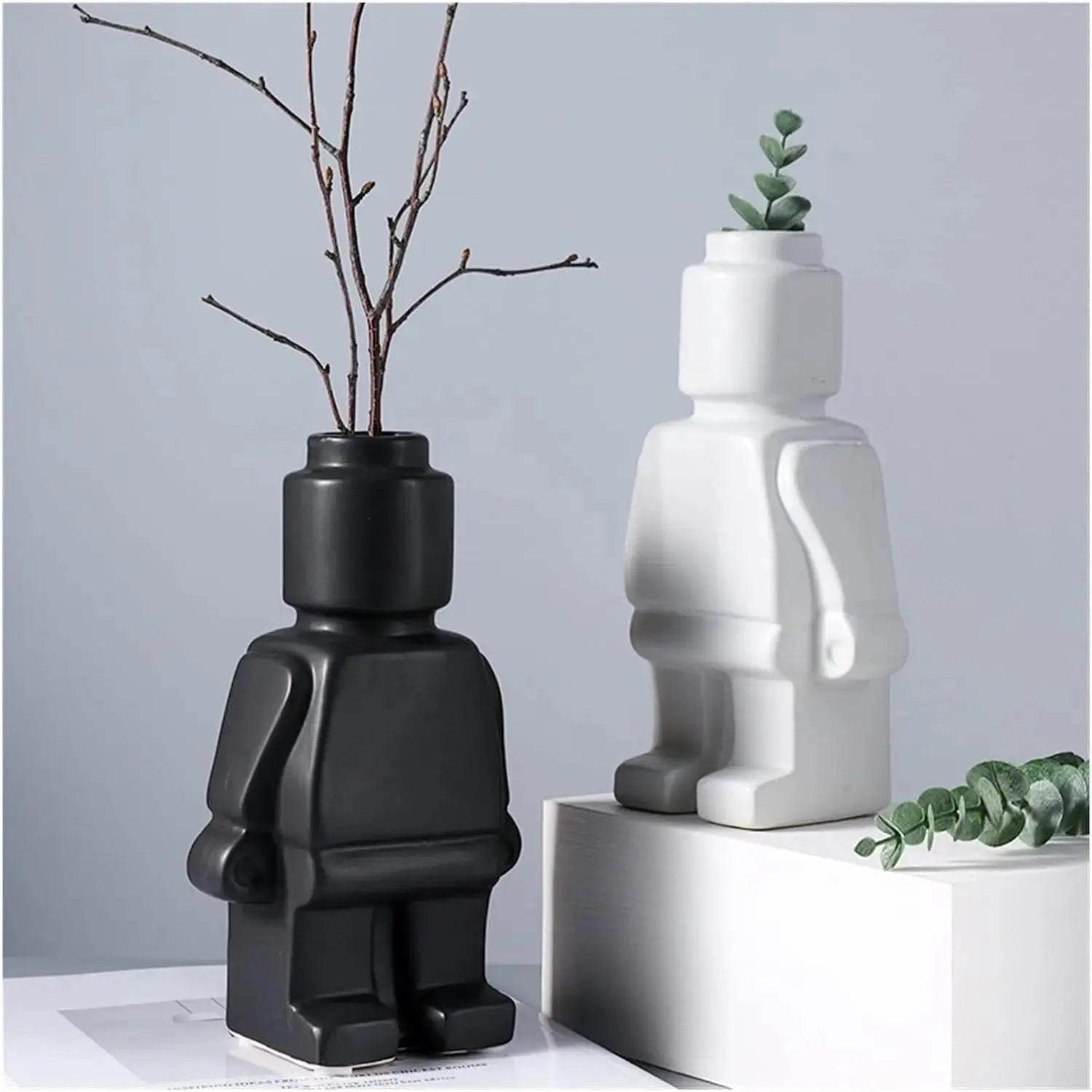 Two Lego Man Vases, one black and one white, designed to look like figures with a decorative plant in each.