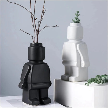Two Lego Man Vases, one black and one white, designed to look like figures with a decorative plant in each.