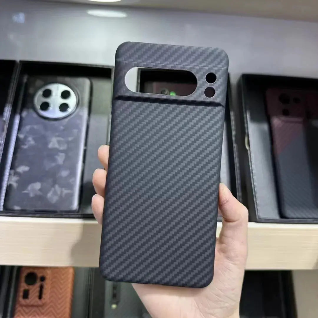 Person holding a black carbon fiber phone case with a blurred background