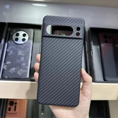 Person holding a black carbon fiber phone case with a blurred background