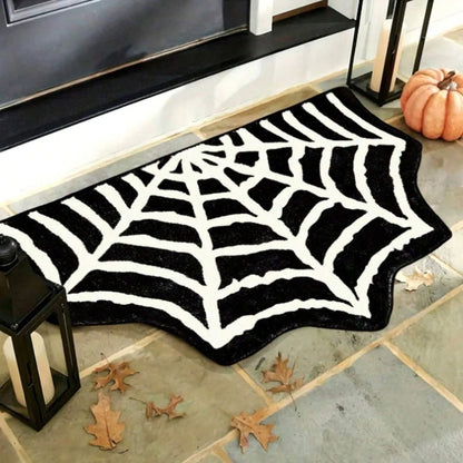 Black and white spider web doormat on a stone floor with Halloween decorations.
