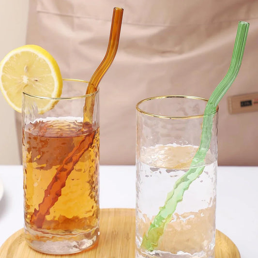 Two wavy glass straws in amber and green used in drinks, showcasing their stylish design and versatility for iced tea or water in kitchen settings.