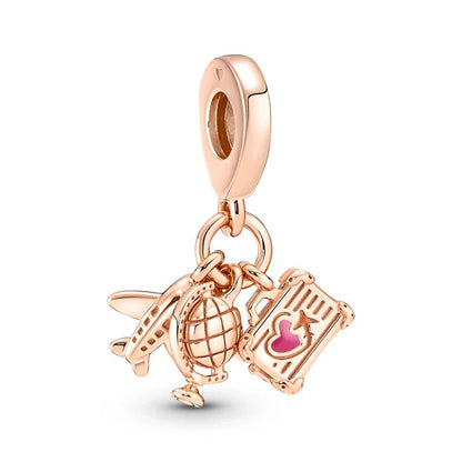 Rose gold charm with airplane, globe, and suitcase on a white background
