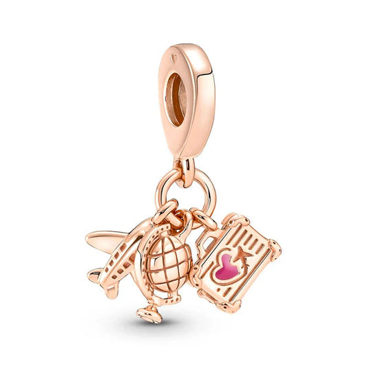 Rose gold charm with airplane, globe, and suitcase on a white background