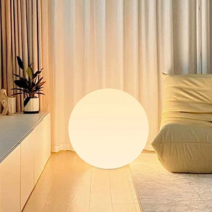 Round glowing lamp on a wooden floor with curtains and a plant in the background