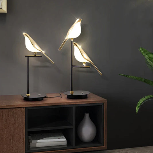 Modern table lamp with bird design on a wooden side table against a dark wall.
