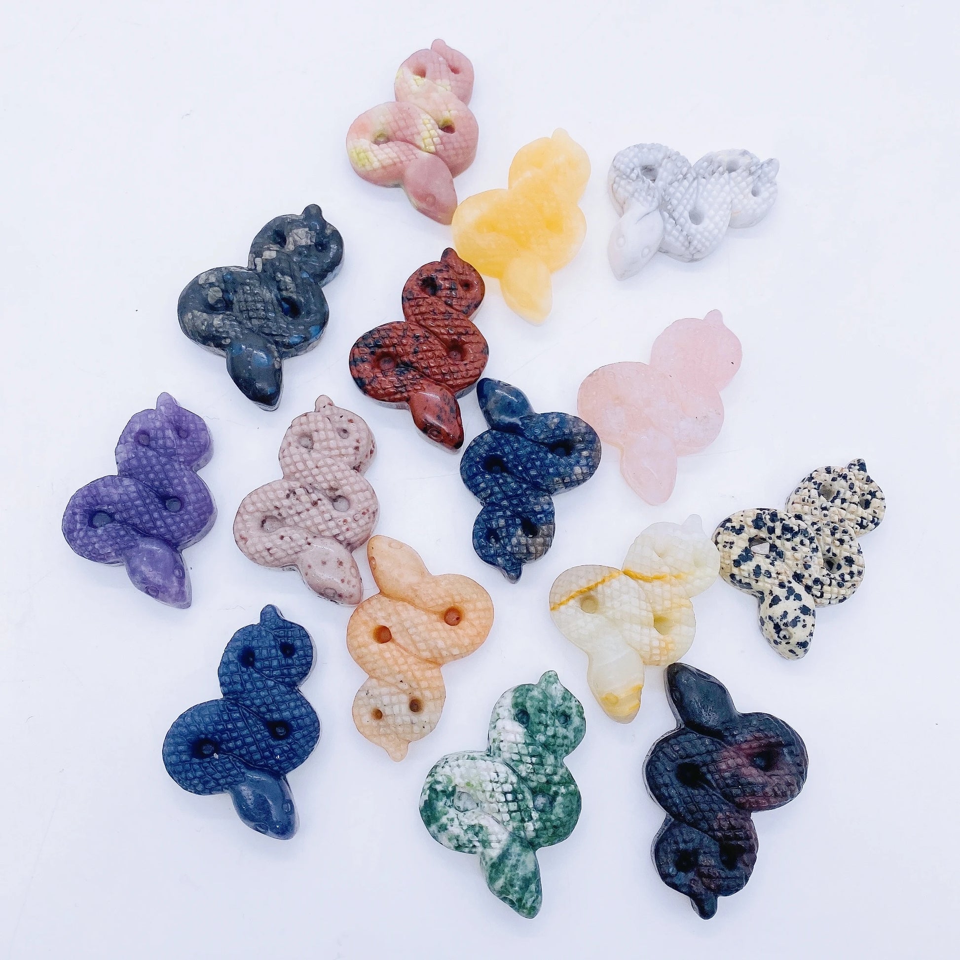A collage of various crystal snake statues in different colors held in a person's hand.