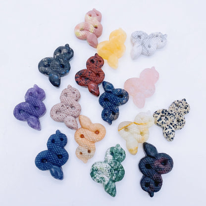 A collage of various crystal snake statues in different colors held in a person's hand.