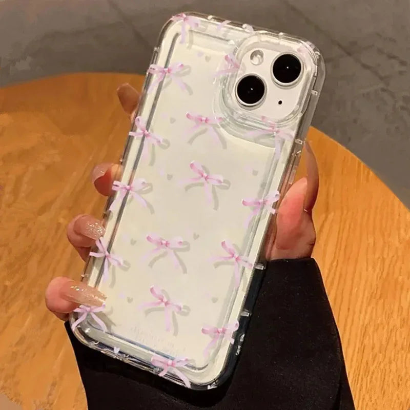 Phone case with pink bow pattern held by a person on a wooden surface