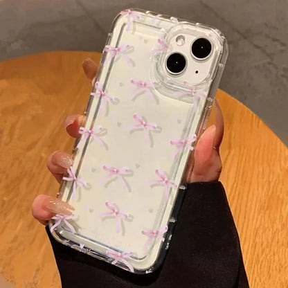Phone case with pink bow pattern held by a person on a wooden surface