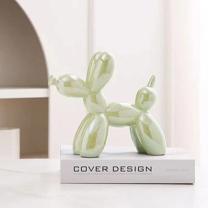 Green balloon dog sculpture on a white surface with 'Cover Design' book in the background
