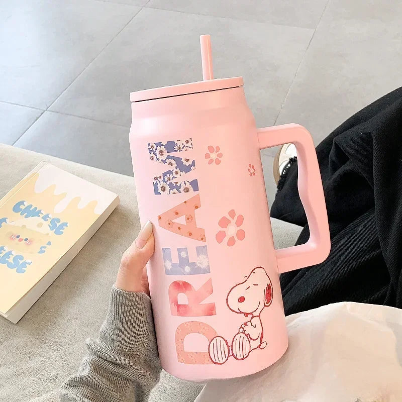 Snoopy Pink tumbler with cartoon character and 'Dream' text held by a person on a light gray surface.