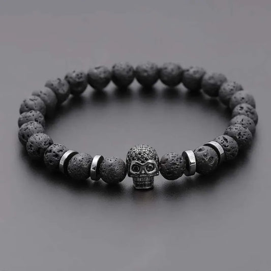 Bracelet with dark stone beads and a skull charm on a gray background