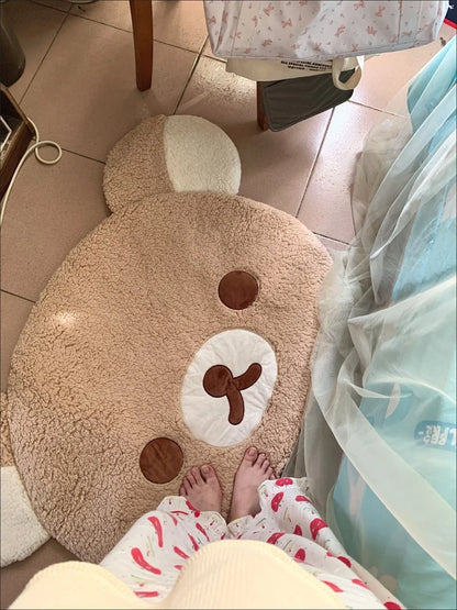 Plush bear-shaped rug on a tiled floor with a person wearing pajamas partially visible.