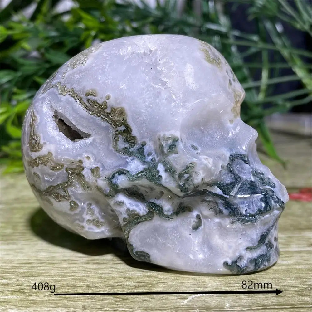 Crystal skull with green veining on a wooden surface with grass in the background