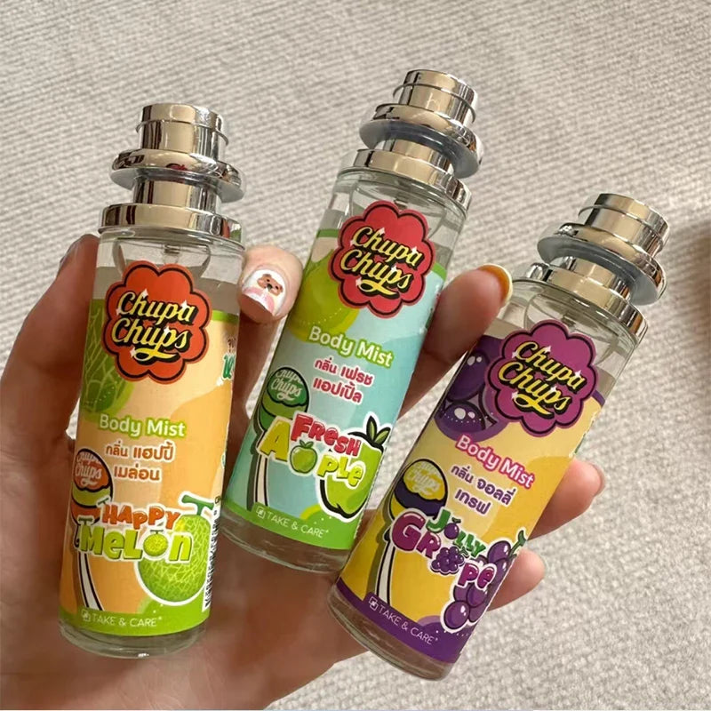 Three 'Chup Chups' body mist bottles held by a hand on a neutral background