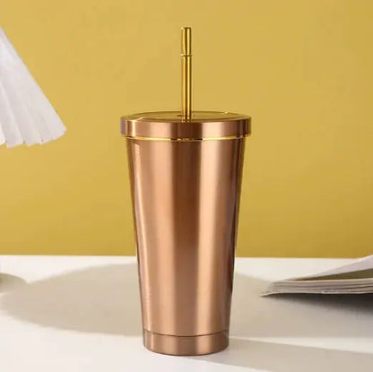 Rose gold tumbler with a straw on a yellow background