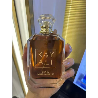 Perfume bottle labeled 'KAY ALI' held in a hand with a blurred background