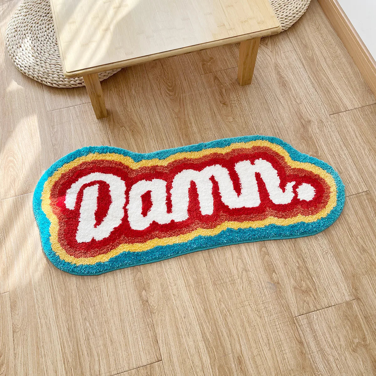 Colorful rug with 'Damu' text on a wooden floor