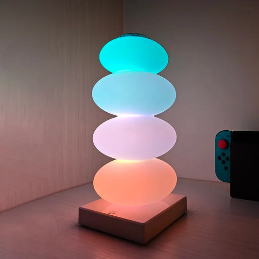 Stack of colorful round lights on a wooden surface with a remote control in the background.