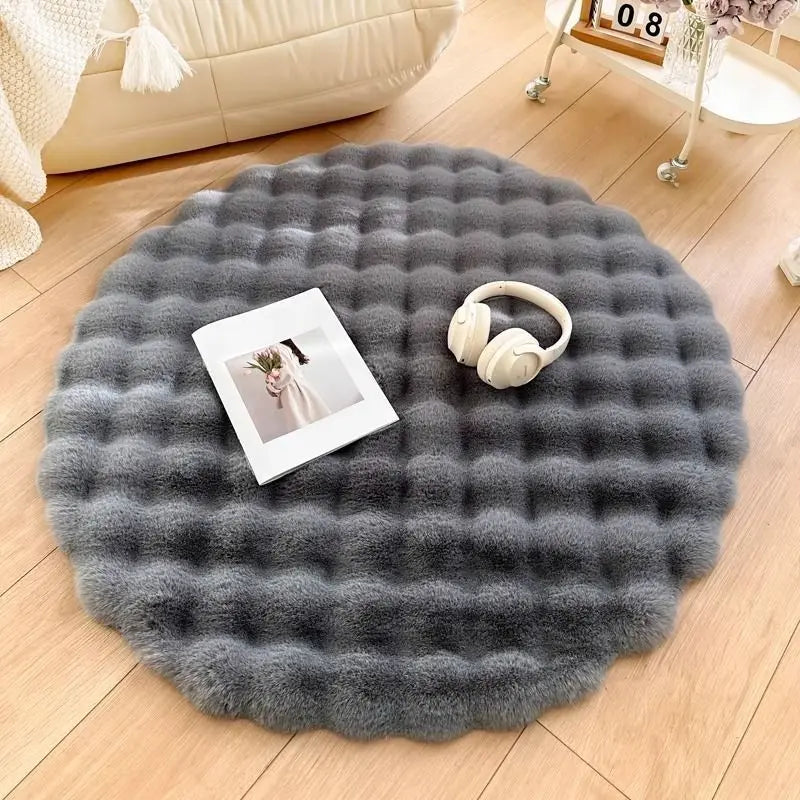 Round gray fluffy rug on a wooden floor with a book and headphones on top