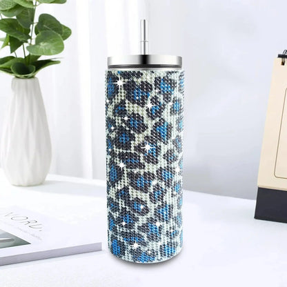 Tumbler with blue and black pattern on a white surface with a plant and notebook in the background