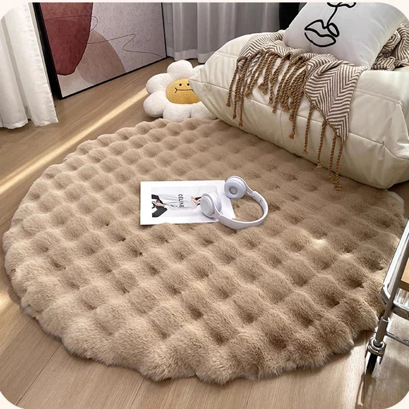 Round beige rug on a wooden floor with a sofa and decorative items in the background