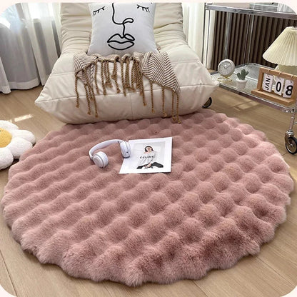 Round pink rug on a wooden floor with a chair and decorative items in the background.