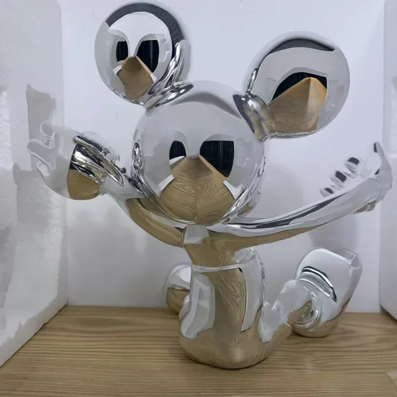 Metallic sculpture of a stylized face with circular eyes and a curved mouth on a wooden surface.