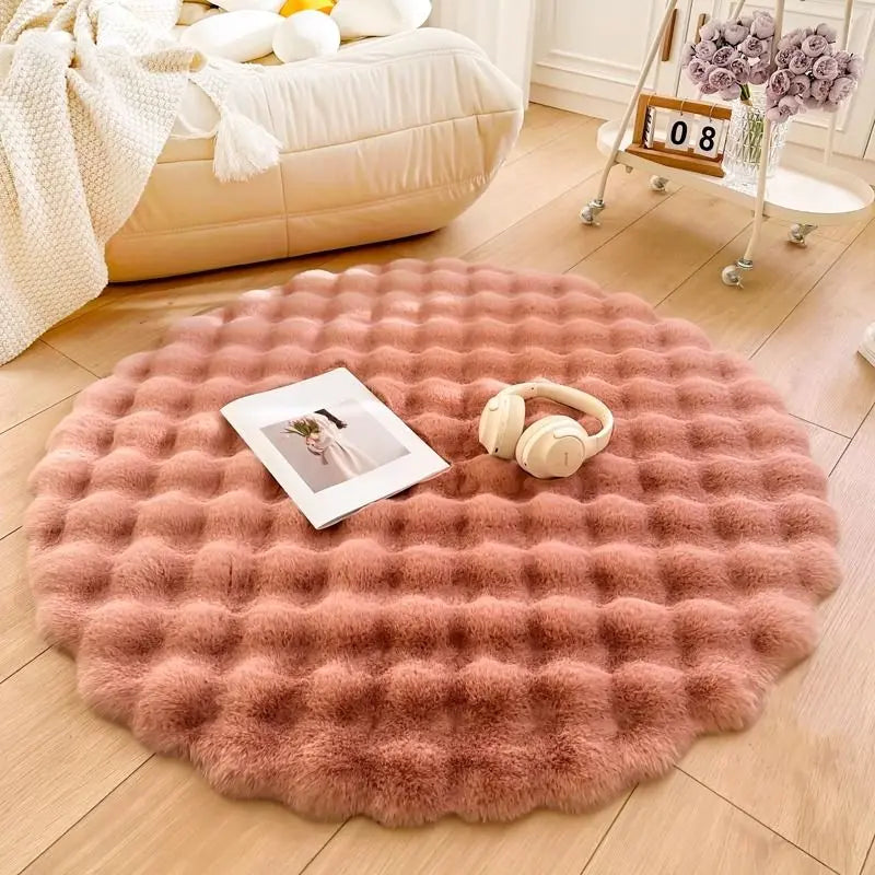 Round pink rug on a wooden floor with a photo and headphones on top, in a cozy living room setting.