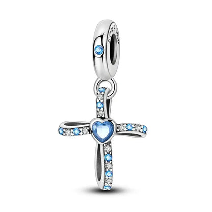 Silver cross charm with blue heart and crystals on a white background