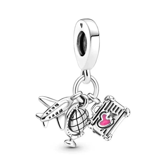 Silver charm with airplane, globe, and suitcase on a white background