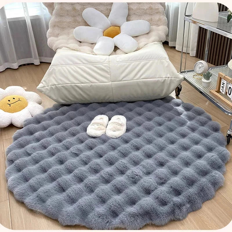 Gray textured rug on a wooden floor with decorative pillows and a flower plush toy in the background.
