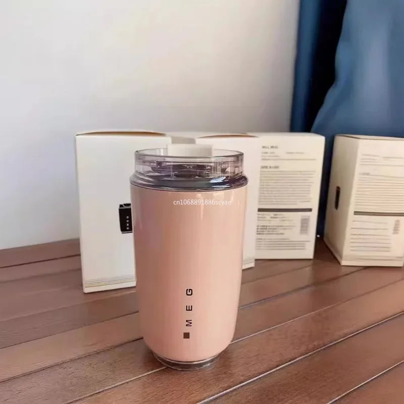 SMEG Pink tumbler with 'SMEG' branding on a wooden surface with boxes in the background