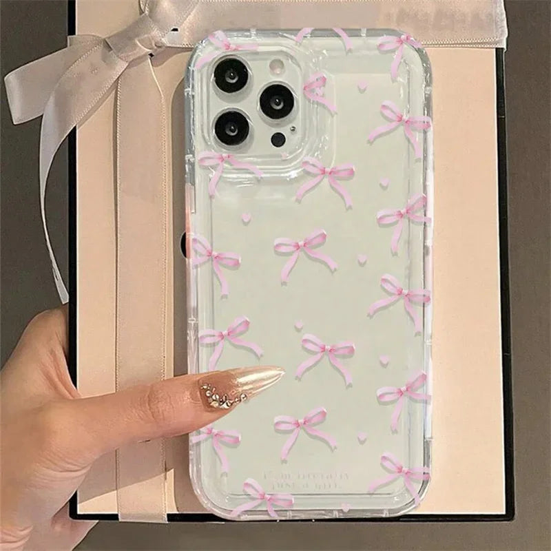 Phone case with pink bows held by a hand against a gift box background