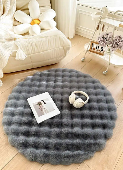 Round gray rug on a wooden floor with a photo and headphones on top, in a cozy living room setting.