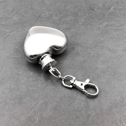 Metallic heart-shaped keychain with clasp on a gray surface