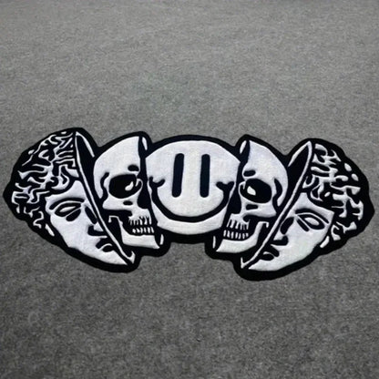 Silver skull and leaf design on a gray background