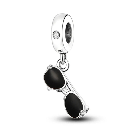 Silver charm shaped like sunglasses with black lenses on a white background