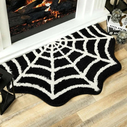 Black spider web rug on a wooden floor in front of a fireplace.