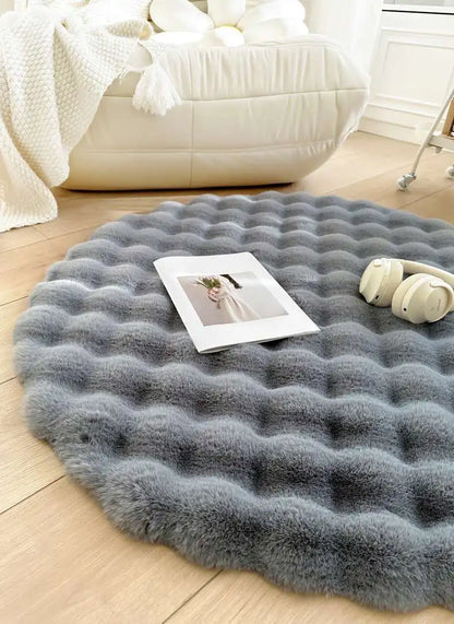 Round gray rug on a wooden floor with a magazine and headphones on top