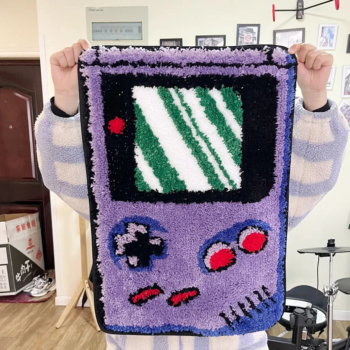 Person holding a purple game console-shaped rug with a striped screen design.