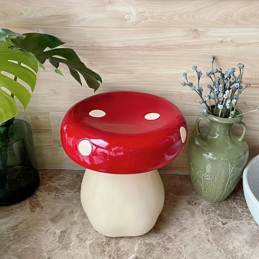 Red and white mushroom-shaped stool on a countertop with a plant and vase in the background.