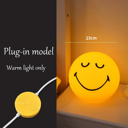 Smiley face night light with plug-in model and warm light only text on a black background.