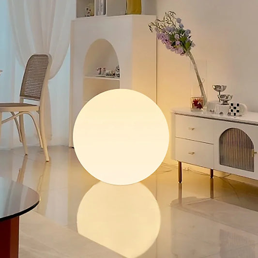 Glowing spherical lamp on a reflective floor in a modern room.