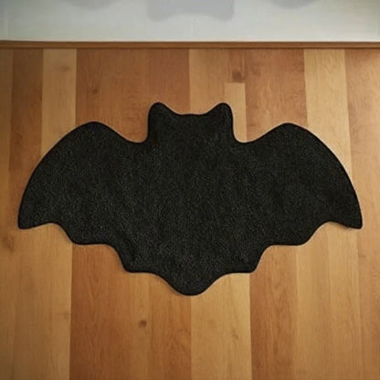 Black bat-shaped mat on a wooden floor